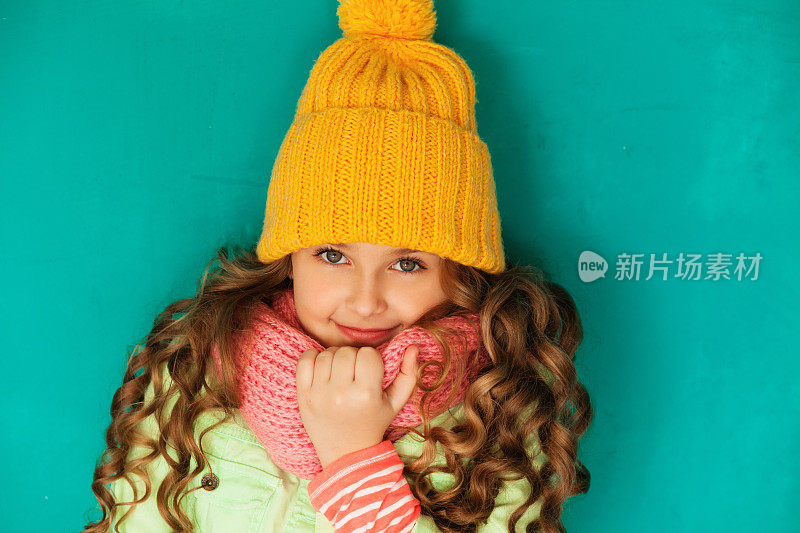 可爱的小姑娘戴着黄色的羊毛帽和暖和的围巾