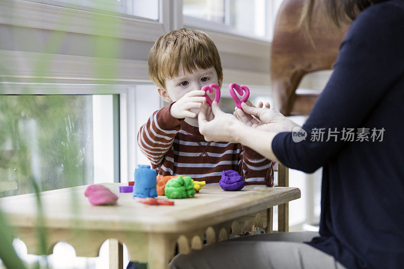 母亲和儿子在家里玩孩子的玩粘土