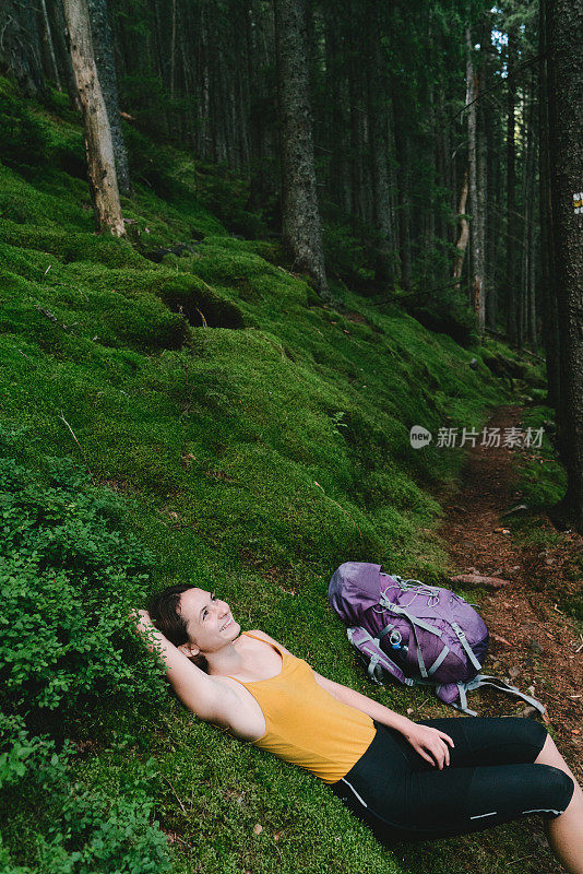 在长满青苔的山林中徒步旅行后休息的女人