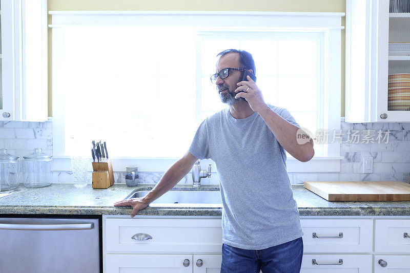 西班牙男子站在厨房里用手机交谈