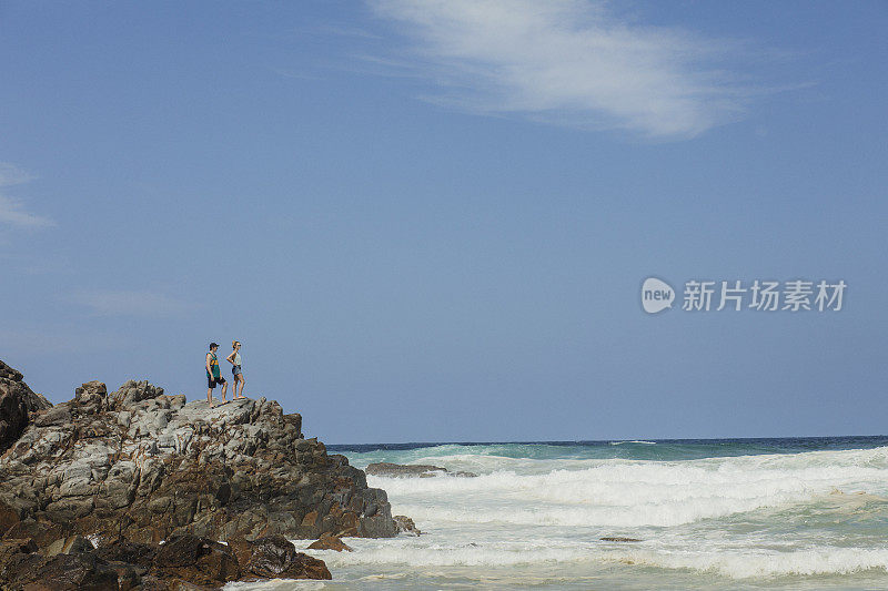 年轻夫妇站在努萨岬的岩石边缘
