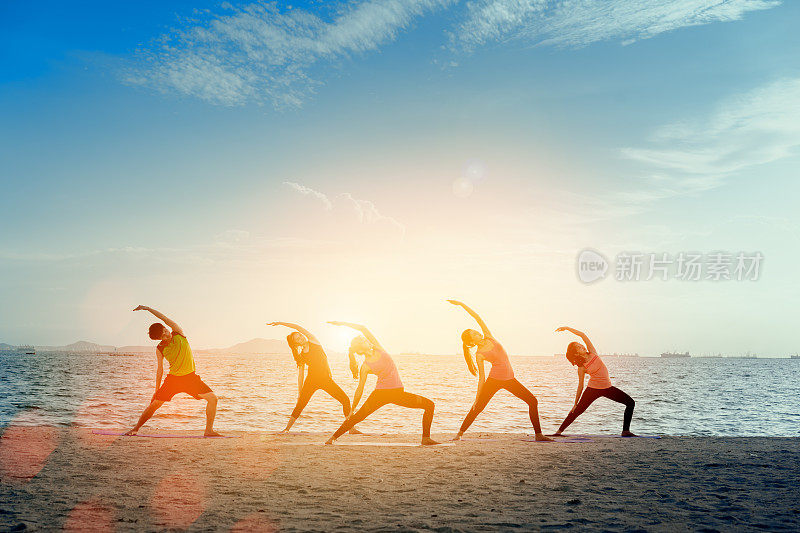 青年组男女瑜伽练习在垫子上放松在课堂运动与姿势健身运动为健康在海滩和海滨现代城市在日出放松假期在夏季假期时间。