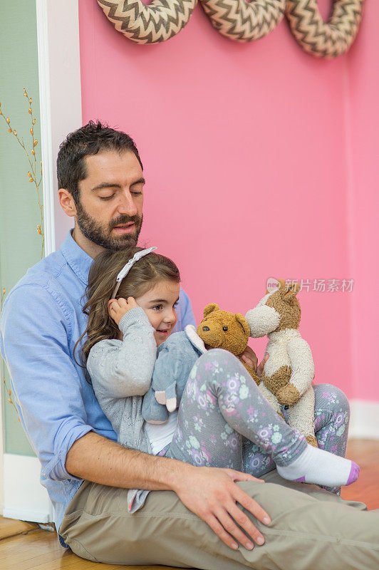爸爸和女儿和她的毛绒玩具依偎在一起