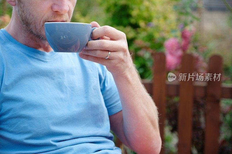 英国，一名男子在花园里啜饮咖啡