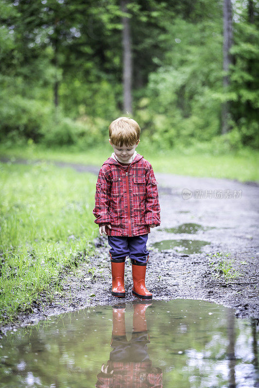 年轻可爱的孩子走着跳进水坑里