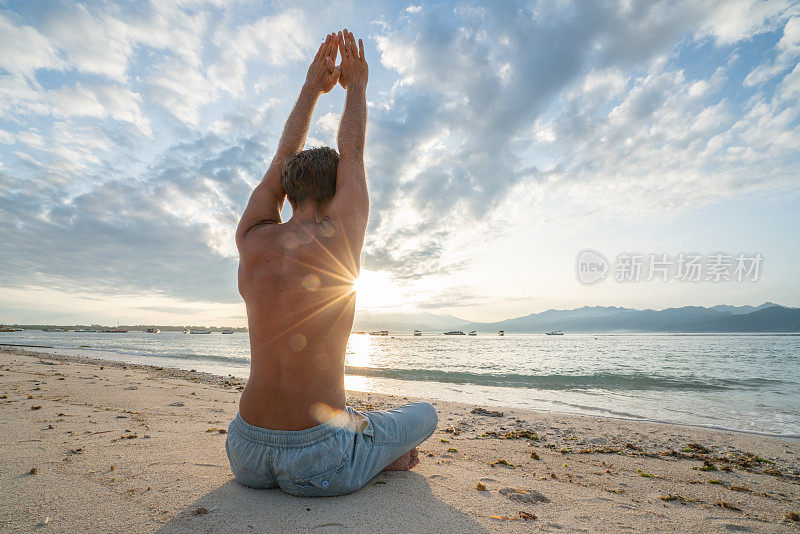 健康的年轻人在日出时在热带气候的海滩上锻炼瑜伽，巴厘岛，印度尼西亚。人的健康平衡理念
