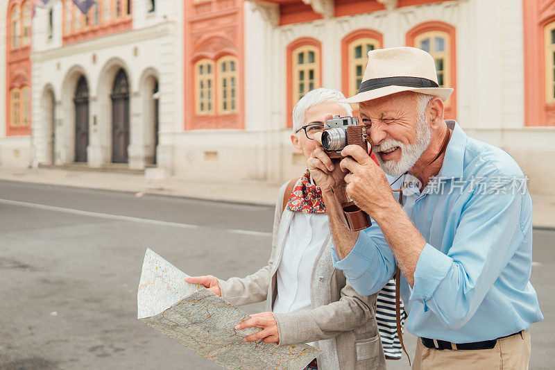 老妇人拿着地图，用相机看着丈夫