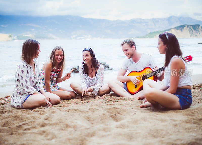一群人在海滩上听吉他