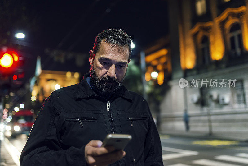 在城市街道上拿着手机的大胡子男人