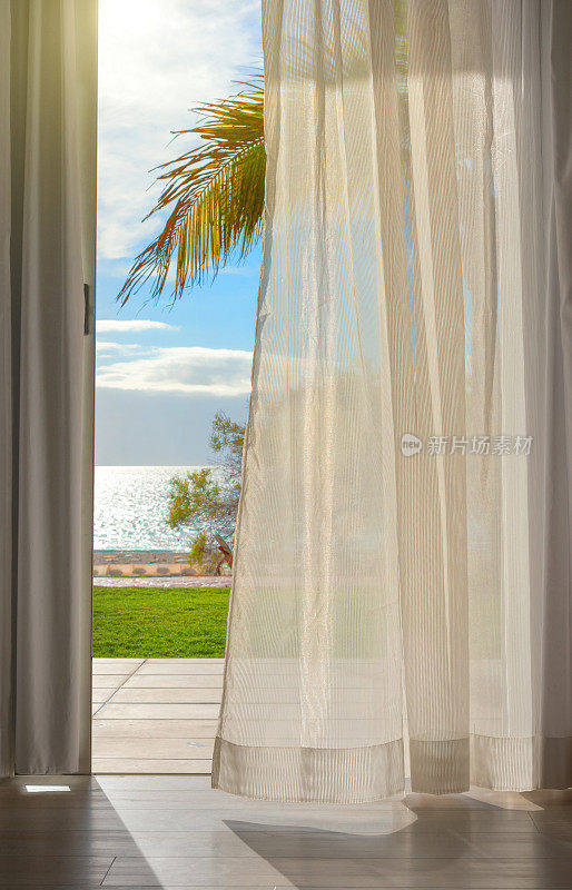 窗帘在风中与棕榈树和海滩的视野