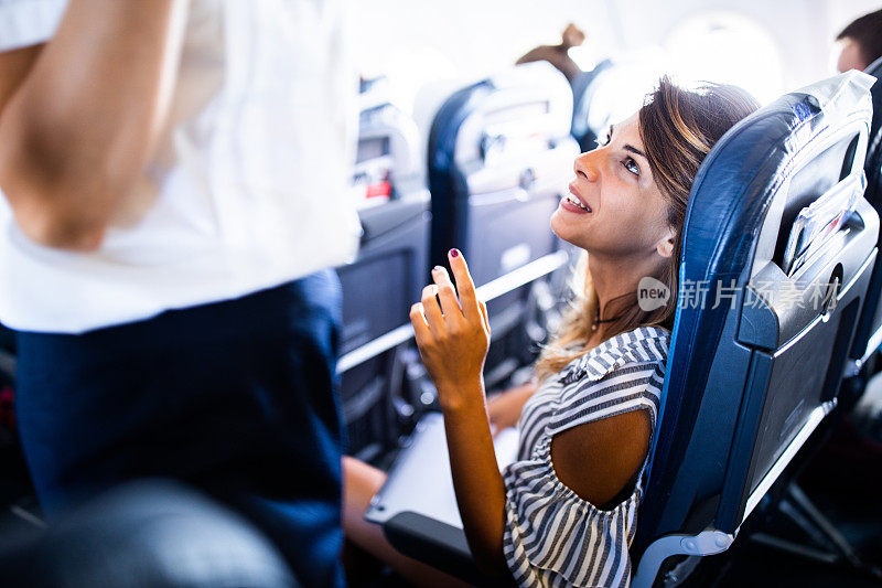 一个快乐的女人在飞机上和空姐聊天。