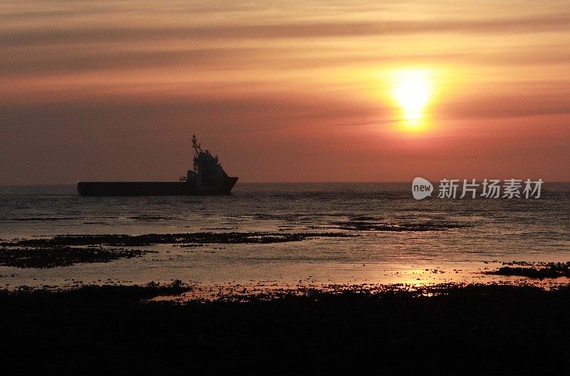 日出越过船，岩石和大海