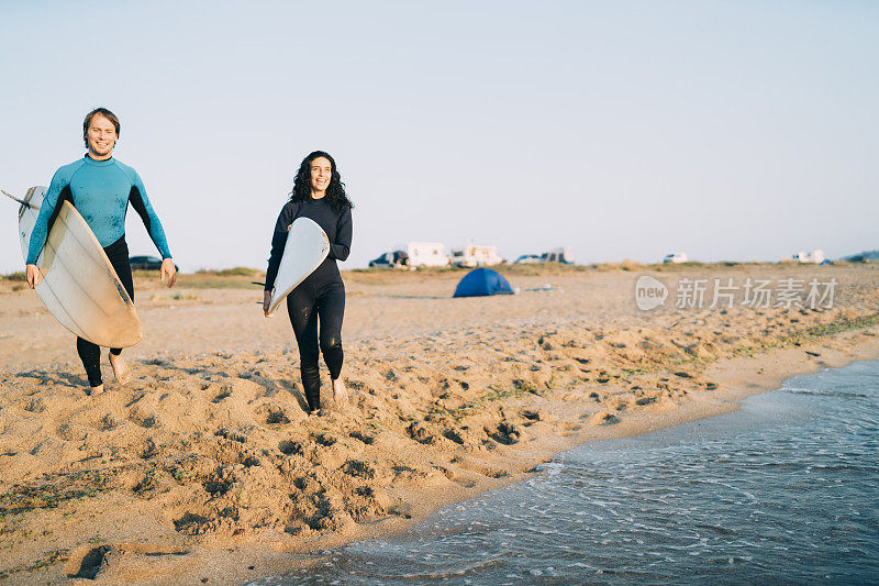 在沙滩上行走并携带冲浪板的冲浪者