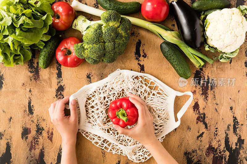 俯视图有机生态蔬菜购物袋在木制桌子的背景。