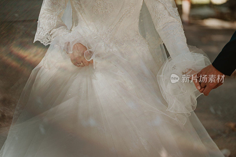 新娘和新郎牵手的特写镜头。新娘和新郎手牵手的细节。