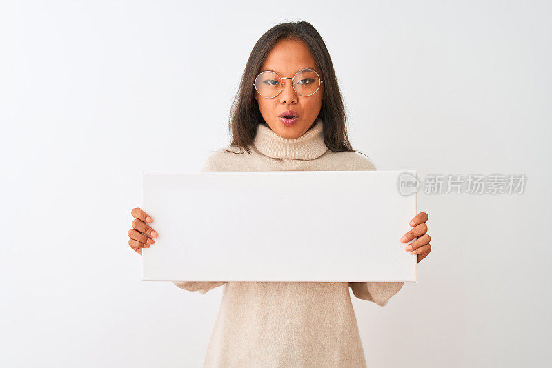 年轻美丽的中国女人戴着眼镜举着旗帜在孤立的白色背景吓了一跳，吃惊的脸，害怕和兴奋的恐惧表情