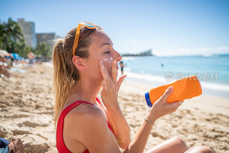在海滩上涂防晒霜的女人