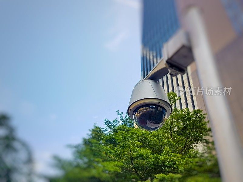 办公大楼前的人行道上有监控摄像头。记录智能现代建筑区域标准安全系统的情况。帮助预防犯罪。