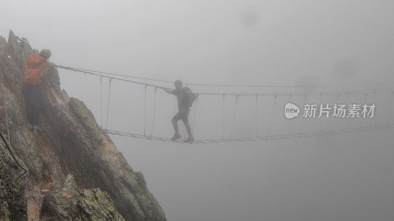 登山运动员从山上爬上吊桥
