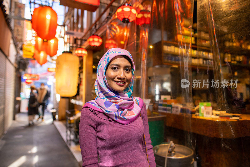 亚洲妇女戴着头巾走在日本居酒屋小巷