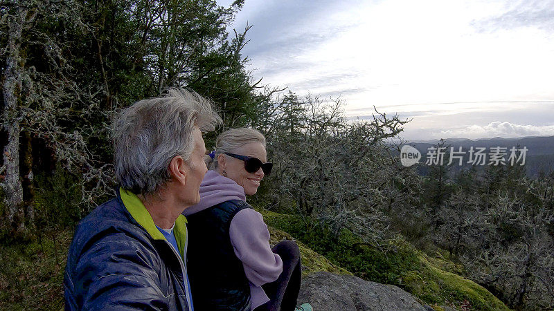 成熟的夫妇在山脊上放松，在山谷之上