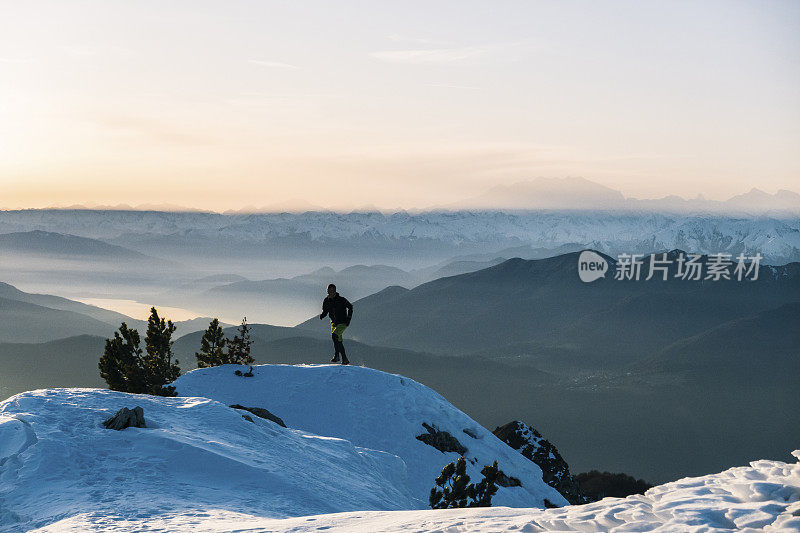 黎明时分，一名徒步运动员爬上雪山的山脊