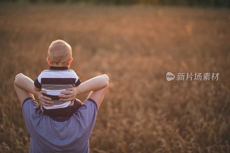 女人抱着孩子在金黄的麦穗地里种庄稼。