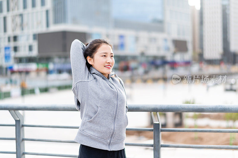 亚洲年轻女子站和伸展后，在城市跑步