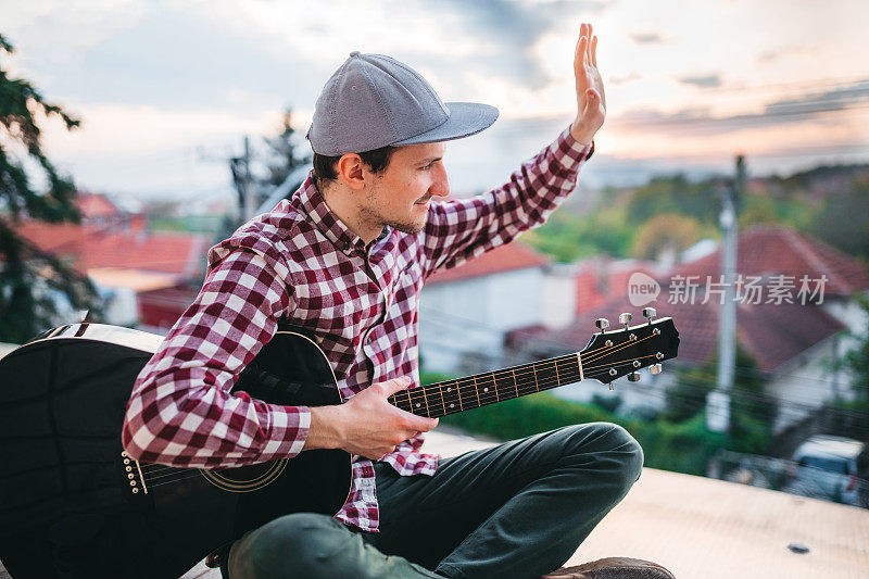社会距离。一个年轻人在院子里弹吉他，招待邻居