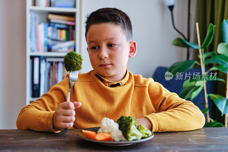 孩子对不得不吃蔬菜很不高兴。他的盘子里有许多蔬菜。他讨厌蔬菜。