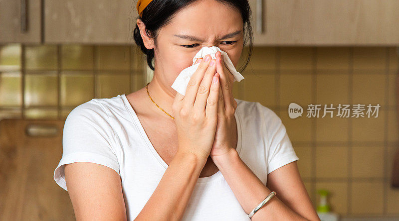 在家里用手帕擤鼻子的亚洲妇女