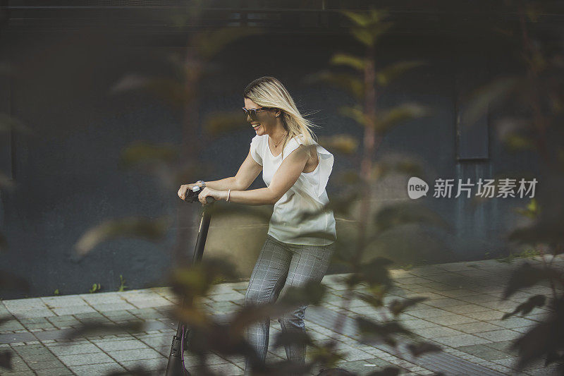 年轻的女商人在城市里骑摩托车