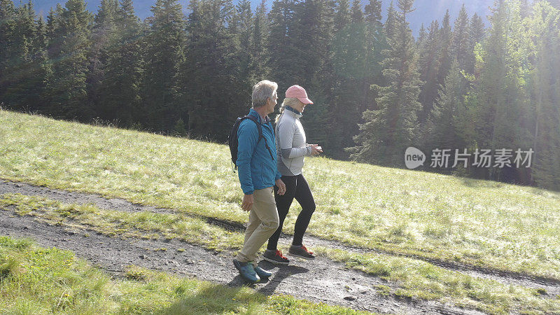 成熟的夫妇沿着乡村的山径徒步旅行
