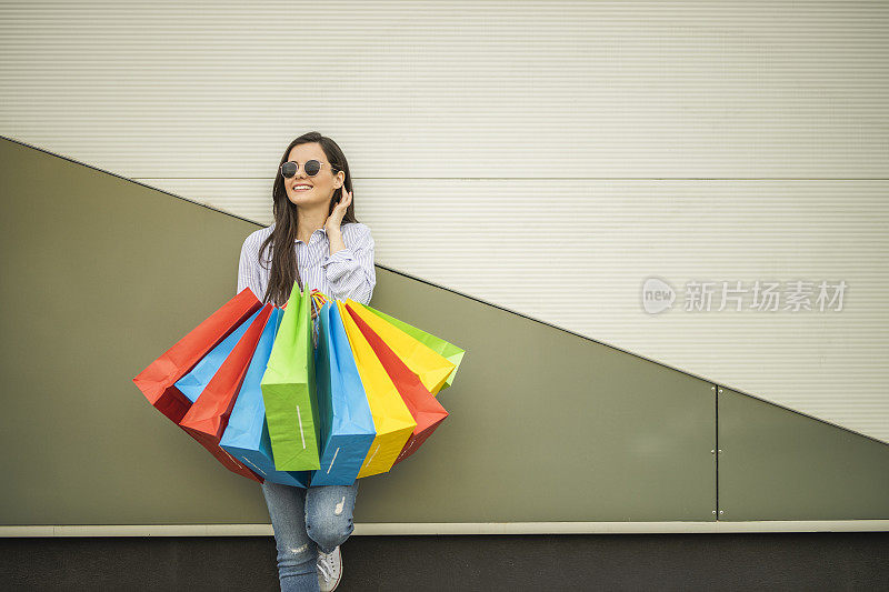 年轻快乐的女人愉快地微笑着她的购物袋孤立在灰色背景与副本空间