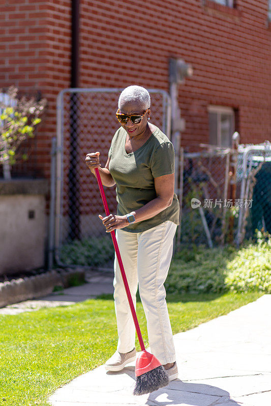 年长的女人清扫她的后院区域