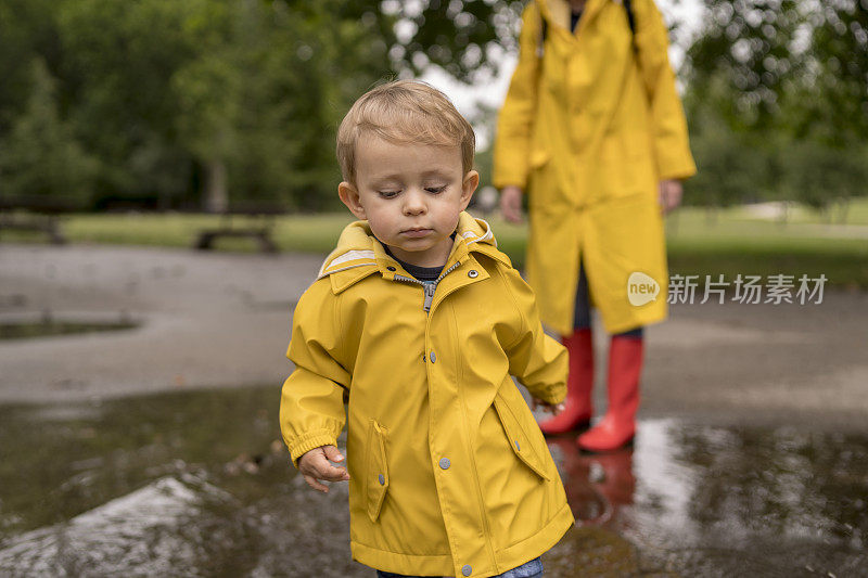 母亲和一个孩子。母亲和儿子穿着雨衣，手牵着手在公园里