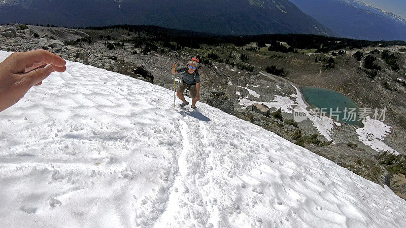 徒步旅行者沿着积雪的山坡跑下去