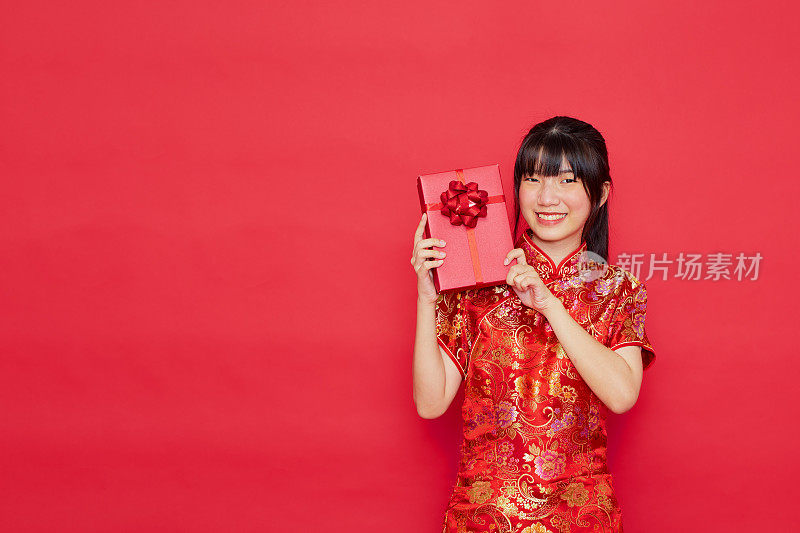 可爱的年轻亚洲女子穿旗袍拿着红色礼盒上的红色