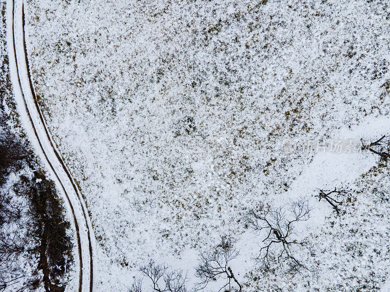 在蜿蜒的泥土路的正上方，旁边是被雪覆盖的草地