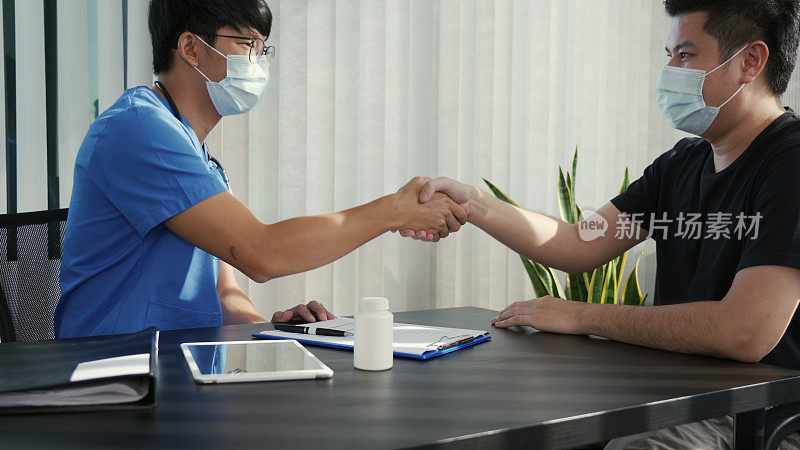 疫情爆发期间，一名亚洲医生戴着口罩与患者握手。