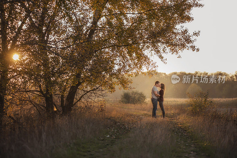 幸福的情侣牵手，拥抱，亲吻，共度时光。一个青年男子和一个女孩走在秋天的森林里。在寒冷的季节旅行，在周末。永浴爱河的情侣