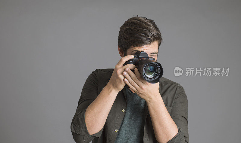 一个摄影师在灰色背景上使用数码单反相机的肖像
