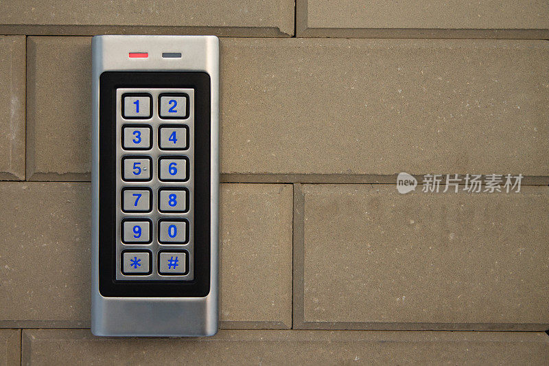 银色对讲机呼叫面板与蓝色数字按钮，在一个砖米色篱笆支柱的私人住宅
