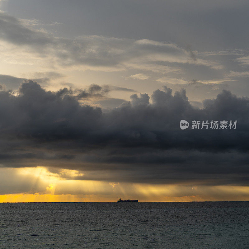 在斯里兰卡的希卡杜瓦，一艘货船在印度洋上空的地平线上，在美丽的日落上。