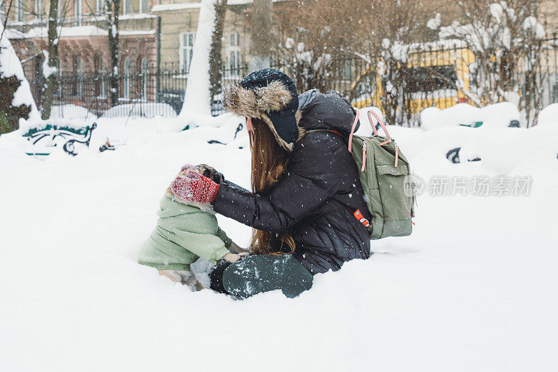 快乐的年轻女子背包享受第一雪在公园散步与小可爱的狗