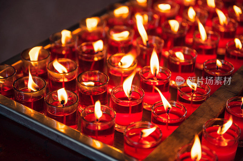 一排虔诚的红烛，玻璃中有火焰