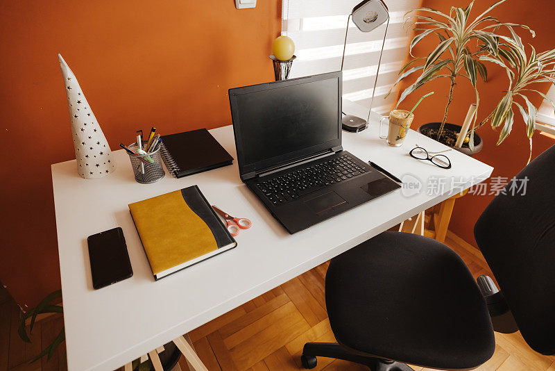 桌上备有笔记本电脑、记事本等办公用品在家中办公