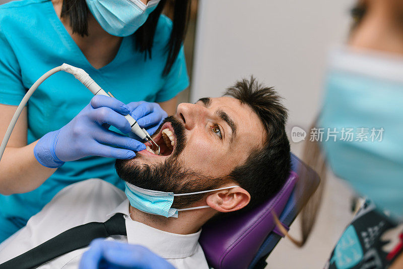 牙医正在给一个年轻人的牙齿钻孔。