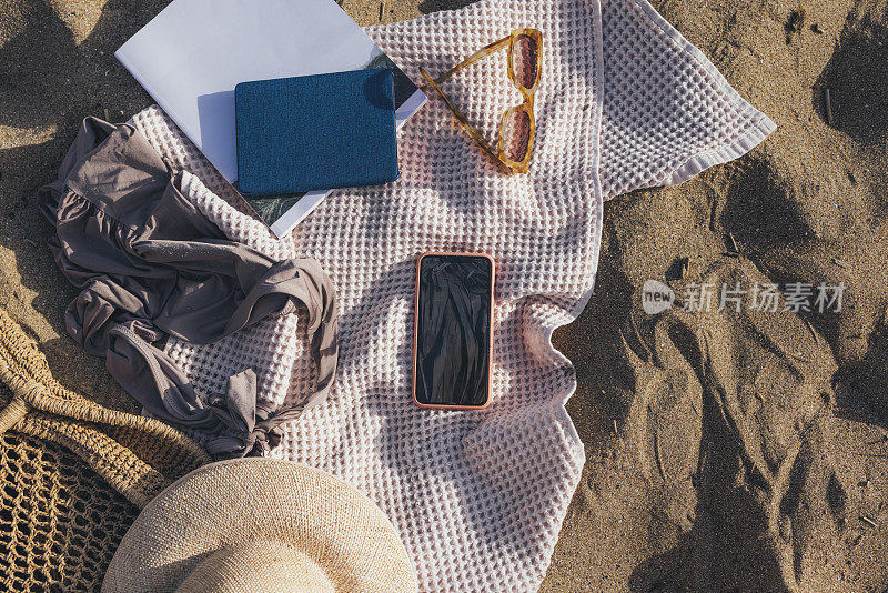 准备好去海边:沙滩上的静物必需品，包括智能手机
