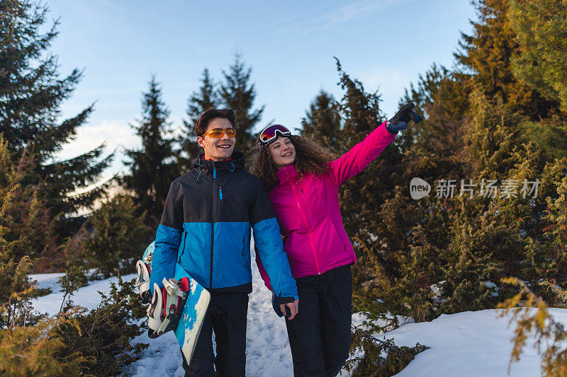 美丽的年轻异性恋夫妇在一个滑雪假期散步在自然而牵手